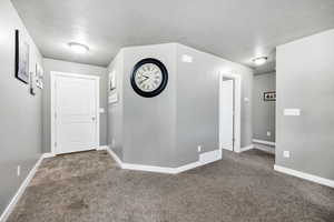 Entryway featuring carpet, baseboards, and a textured ceiling