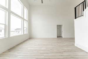 Spare room with ceiling fan, plenty of natural light, a high ceiling, and light wood-style flooring