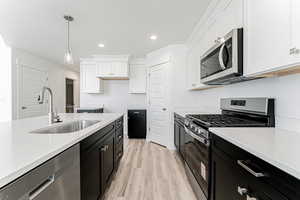 Kitchen with appliances with stainless steel finishes, dark cabinets, white cabinetry, recessed lighting, and light countertops
