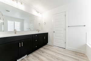 Bathroom featuring double vanity, wood finished floors, and a bath