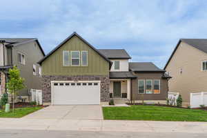 Craftsman house with board and batten siding, a garage, driveway, and a shingled roof