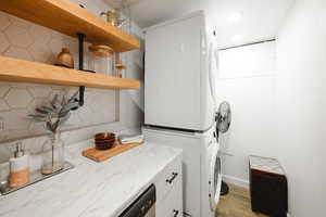 Washroom featuring dark wood-style flooring and stacked washer and clothes dryer