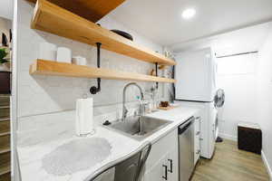 Kitchen featuring white cabinetry, light countertops, tasteful backsplash, light wood-type flooring, and open shelves