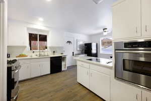 Kitchen featuring black appliances, dark wood-style flooring, white cabinetry, light countertops, and recessed lighting