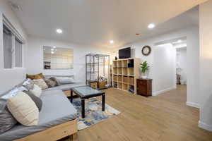 Living room with light wood-type flooring and recessed lighting