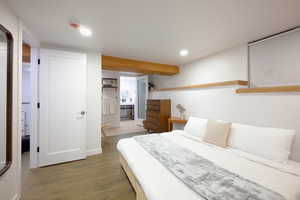 Bedroom with dark wood-type flooring, recessed lighting, and connected bathroom