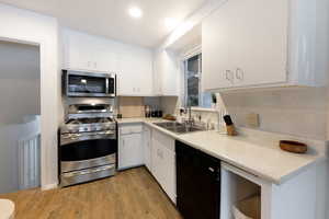 Kitchen featuring appliances with stainless steel finishes, light countertops, dark wood finished floors, white cabinets, and recessed lighting