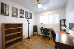Office with light wood-style flooring and ceiling fan
