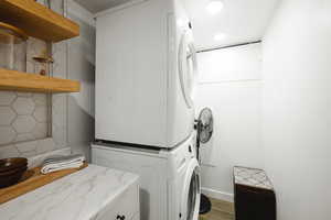 Laundry room with stacked washer / drying machine and wood finished floors