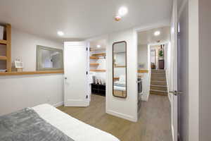Bedroom with wood finished floors, a walk in closet, and recessed lighting