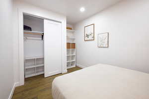 Bedroom with dark wood-type flooring, recessed lighting, and a closet