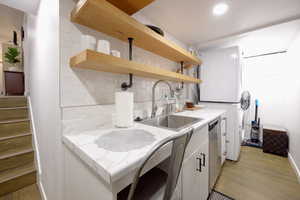 Kitchen featuring open shelves, white cabinets, light countertops, tasteful backsplash, and light wood-style floors