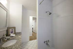 Full bath with light tile patterned floors, vanity, and  shower combination