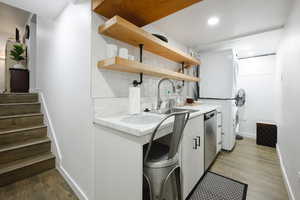 Laundry room with dark wood-style flooring, stacked washer / dryer, and recessed lighting