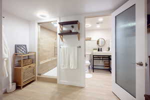 Full bath with a stall shower, light wood finished floors, and vanity