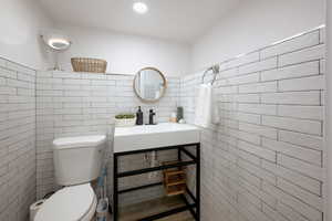 Bathroom featuring toilet and tile walls