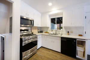 Kitchen featuring stainless steel appliances, dark wood finished floors, light countertops, white cabinetry, and recessed lighting