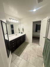 Ensuite bathroom with vanity, a textured ceiling, tile patterned floors, visible vents, and ensuite bathroom