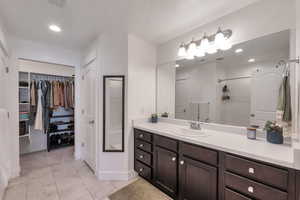 Bathroom with tile patterned floors, a walk in closet, vanity, a shower, and baseboards