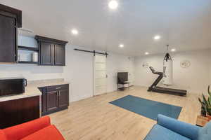 Workout room featuring a barn door, recessed lighting, visible vents, light wood-style floors, and baseboards