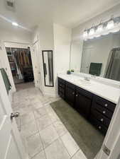 Full bathroom featuring a textured ceiling, visible vents, tile patterned flooring, vanity, and a walk in closet
