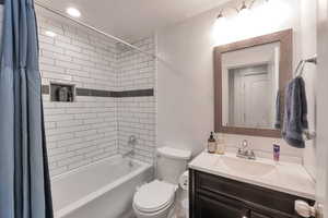 Bathroom featuring toilet, vanity, and shower / bath combination with curtain