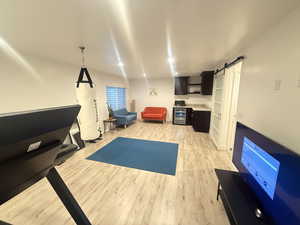 Exercise area featuring recessed lighting, beverage cooler, a barn door, and light wood-type flooring