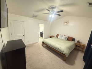 Bedroom featuring light carpet, visible vents, lofted ceiling, and a textured ceiling