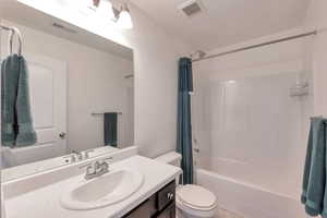 Full bath with shower / bath combination with curtain, visible vents, vanity, and toilet