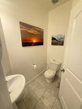 Half bathroom featuring toilet, a sink, tile patterned flooring, baseboards, and visible vents