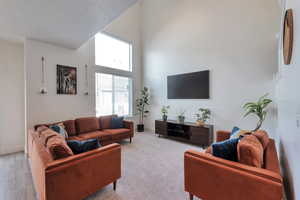Living area with baseboards and a towering ceiling