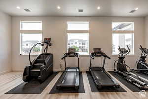 Gym with a wealth of natural light, wood finished floors, and recessed lighting