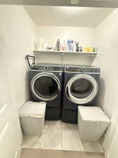 Laundry area with separate washer and dryer, laundry area, and a textured ceiling