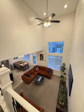 Living area featuring a high ceiling, a ceiling fan, baseboards, and recessed lighting