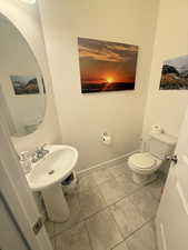 Half bath featuring baseboards, toilet, and tile patterned floors