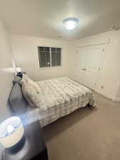 Bedroom with baseboards, a textured ceiling, visible vents, light carpet, and a closet