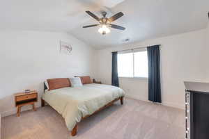 Bedroom with lofted ceiling, visible vents, baseboards, light colored carpet, and ceiling fan