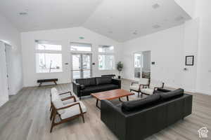 Living area featuring a wealth of natural light, visible vents, high vaulted ceiling, and light wood-style flooring