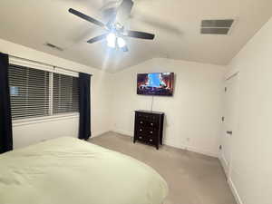 Bedroom with light carpet, baseboards, visible vents, and lofted ceiling