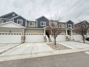 View of front facade with stucco siding, a garage, and concrete driveway