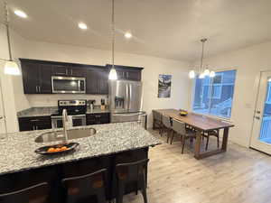 Kitchen with a sink, stainless steel appliances, light wood-style floors, and a notable chandelier