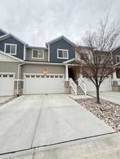 View of front facade featuring stone siding, concrete driveway, and stucco siding