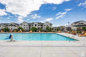 Community pool with a residential view, fence, and a patio