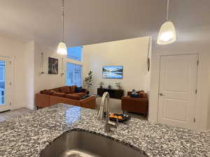 Kitchen featuring dark stone counters, open floor plan, a sink, and decorative light fixtures