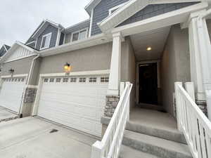Property entrance featuring stucco siding, an attached garage, and stone siding