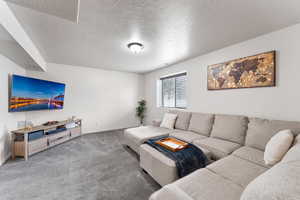 Carpeted living area featuring baseboards and a textured ceiling
