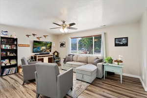 Living room with baseboards, ceiling fan, visible vents, and light wood finished floors