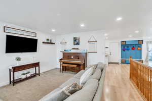Living room featuring light wood finished floors, baseboards, light carpet, and recessed lighting