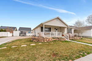 View of front facade featuring a front lawn, covered porch, and fence