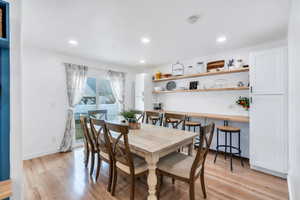 Dining area with ample space for large gathering, sliding doors, open shelves, light wood-style flooring, and recessed lighting